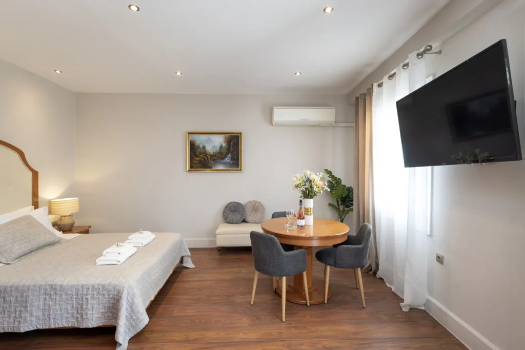 Inside look of the Suite room of Hotel Palladion featuring a large double bed and a flat screen tv mounted on the wall