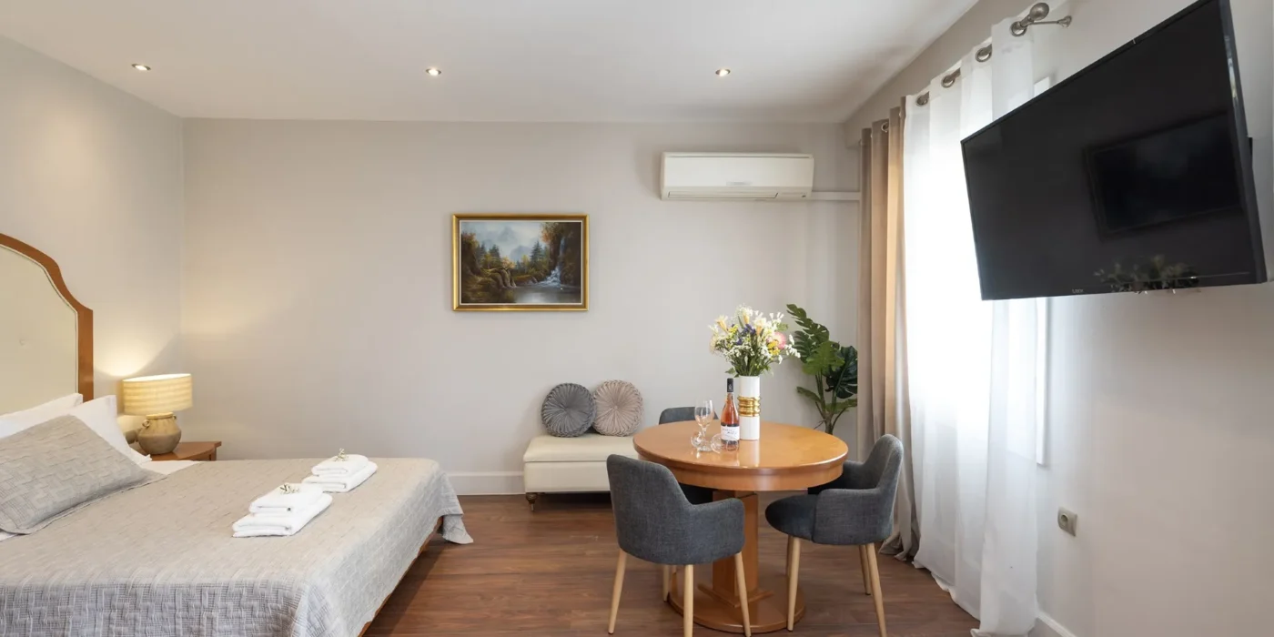 Inside look of the Suite room of Hotel Palladion featuring a large double bed and a flat screen tv mounted on the wall